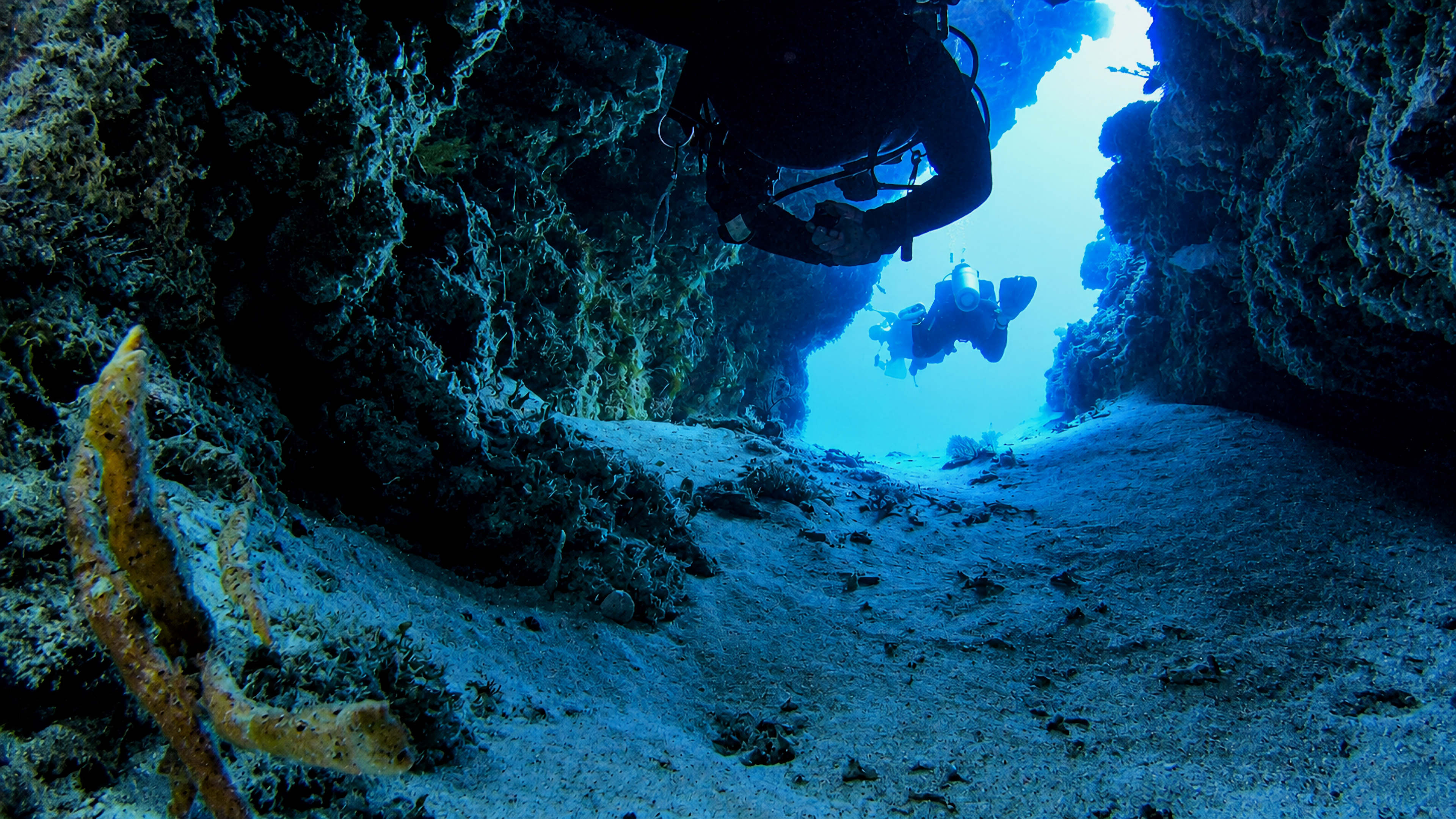Divers exiting a Palancar swim-through into bright blue water